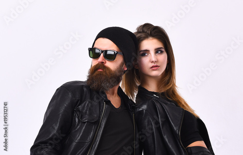 Girl and bearded man in black leather jacket and hat.