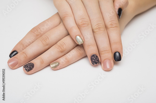 Caviar manicure in yellow black nails with black and gold rhinestones on a yellow background.
