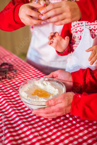 Mom and son break the egg for dough. Father is holding plate of flour. Process of preparing dessert