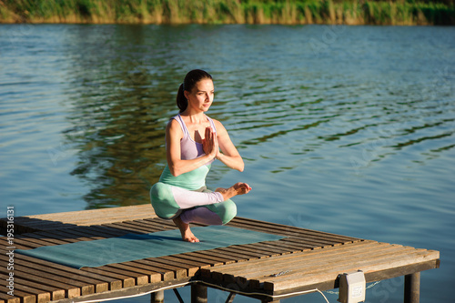 Young healthy woman practicing yoga at sunset