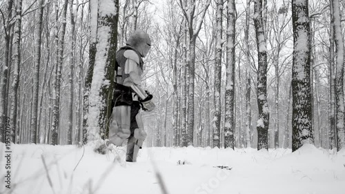 Brave warrior wearing steel armor and helmet walking through winter snowy wood to battlefield in slow motion. Reconstruction of historical times