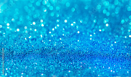 Blue defocused glitter background with copy space. Holiday texture. Wallpaper. Glitter light spots on blue background, defocused