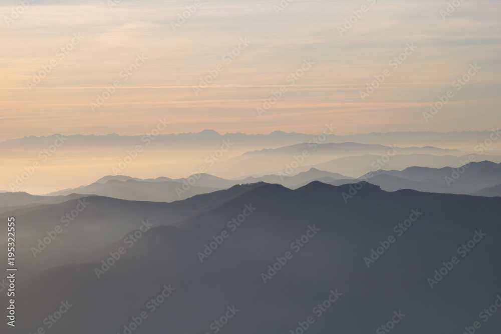 silhouettes of mountains in the middle of the fog  and clouds at sunset