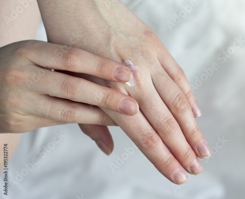 A girl smears a hand cream on a white background