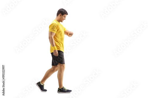 Young man walking and looking at his watch