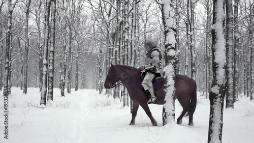 Portrait of medieval horseman wearing steel armor riding through winter forest, among snowy trees in slow motion. Reconstruction of ancient times