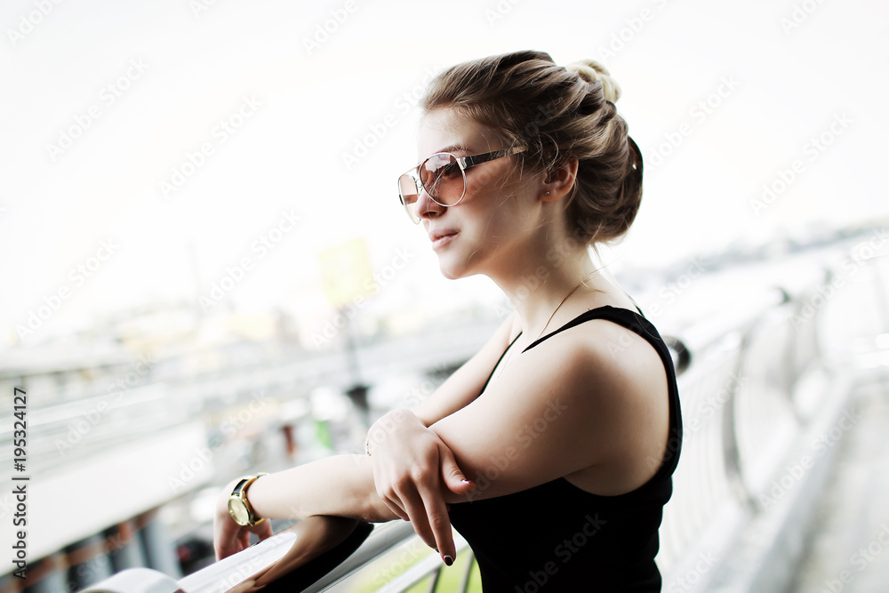 Beautiful fashionable blonde girl in black dress and wearing sunglasses. Open space.