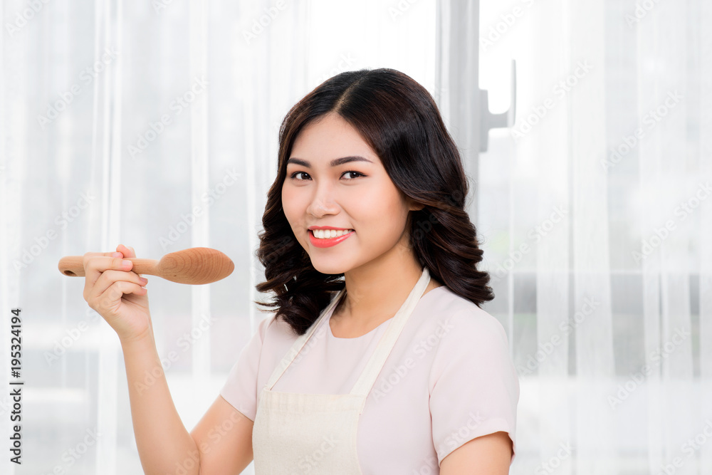 Healthy food. Asian woman cooking in the kitchen with wooden spoon Healthy food. Asian woman cooking in the kitchen with wooden spoon