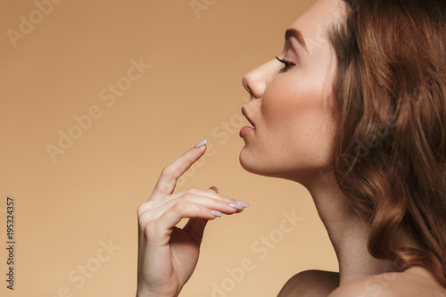 Image of nude amazing woman 20s with long auburn hair posing on camera in profile, isolated over beige background