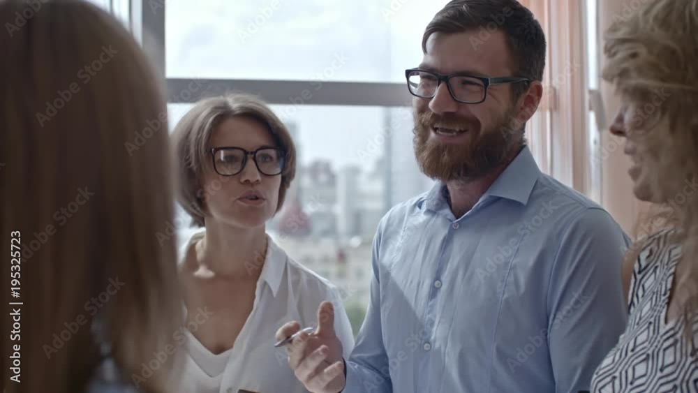 Medium shot of group of colleagues standing in circle, sharing information that they have in their notebooks and smiling, tilt up shot Medium shot of group of colleagues standing in circle, sharing information that they have in their notebooks and smiling, tilt up shot
