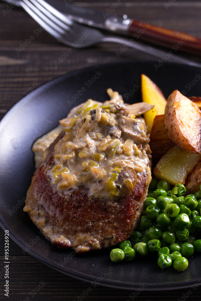Beef steak with mushroom cream sauce, potato wedges  and green peas