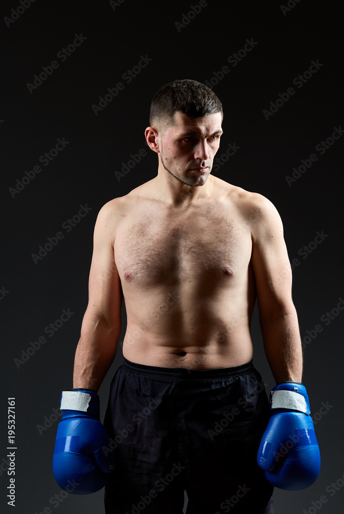 Low key studio portrait of handsome muscular fighter practicing boxing on dark blurred background Low key studio portrait of handsome muscular fighter practicing boxing on dark blurred background