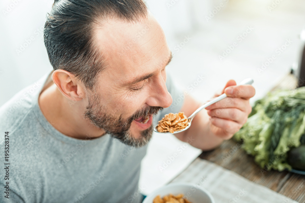 Eat more. Funny pleasant handsome man having breakfast in the kitchen opening mouth and eating. Eat more. Funny pleasant handsome man having breakfast in the kitchen opening mouth and eating.