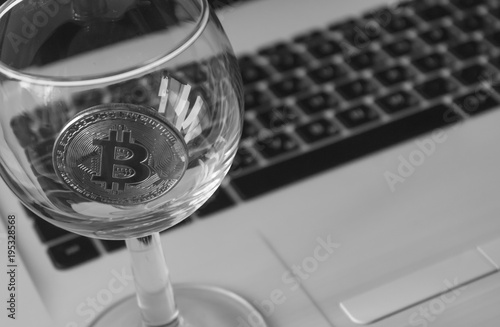 bitcoin in a glass on laptop background