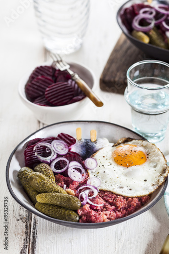 Labskaus, rollmops, pickled gherkin, beetroot salad, onion and fried egg photo