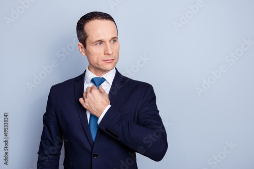 Portrait with copy space of stunning, perfect, corporate man correcting, holding hand on tie, preparing for event, conferention, standing over gray background