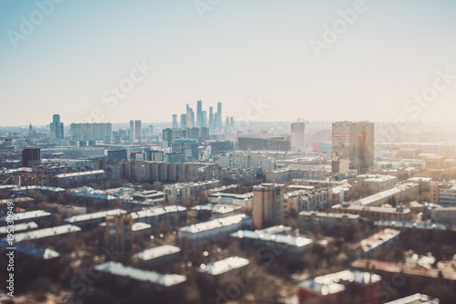 True tilt-shift view of autumn or spring cityscape with skyscrapers and residential houses  with focus on the middle zone of the image  background and foreground are blurred and have strong bokeh