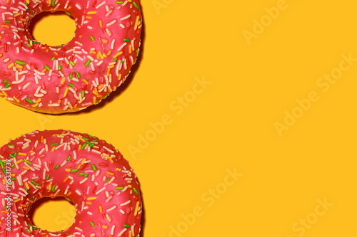 Raspberry donut with icing on a yellow background. Top view.  Minimalism