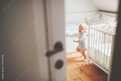 Cute toddler boy running in a bedroom.