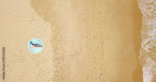 Aerial View From Flying Drone Of Young Woman Relaxing And Getting A Tan On Beautiful Lonely Beach At The Ocean