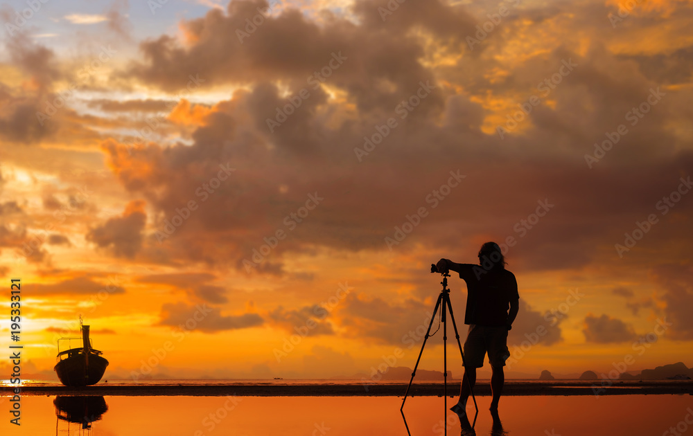 Silhouette of a photographer with tripod on beautiful tropical sunset