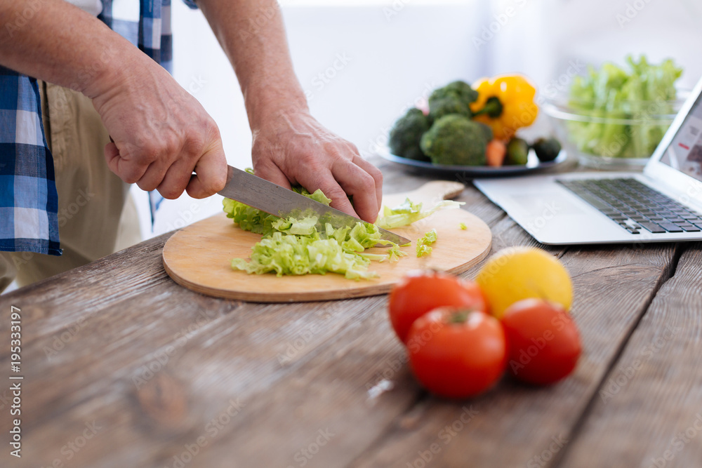 Progressive nutrition. Strong male handsome hands chopping lettuce while using knife and cooking salad