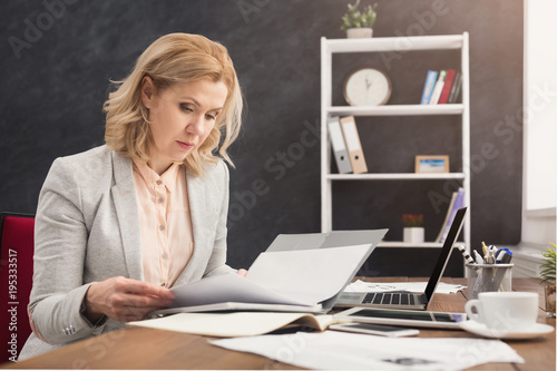Businesswoman reading document at office desktop