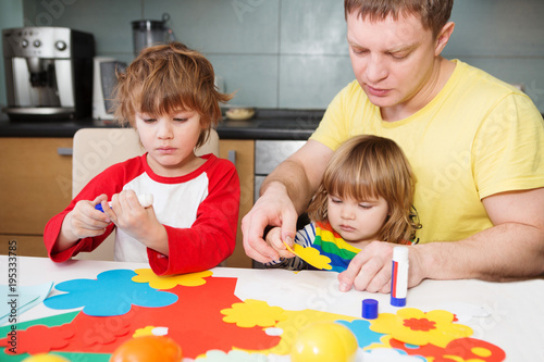 father and the children prepare together Paper decor. children's creativity. Tools and materials for children's art creativity on table. Easter decor.