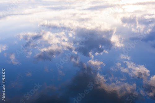 Reflection of blue sky and white clouds in water.