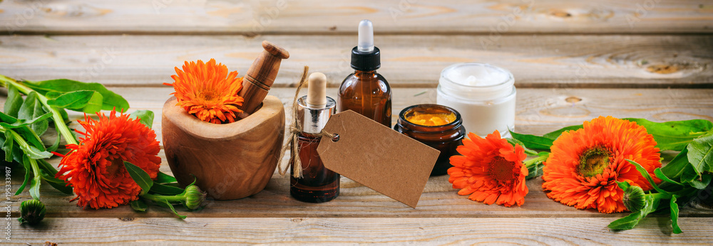 Calendula aromatherapy. Essential oil and cosmetics, blank tag, banner. Wooden table background - obrazy, fototapety, plakaty 