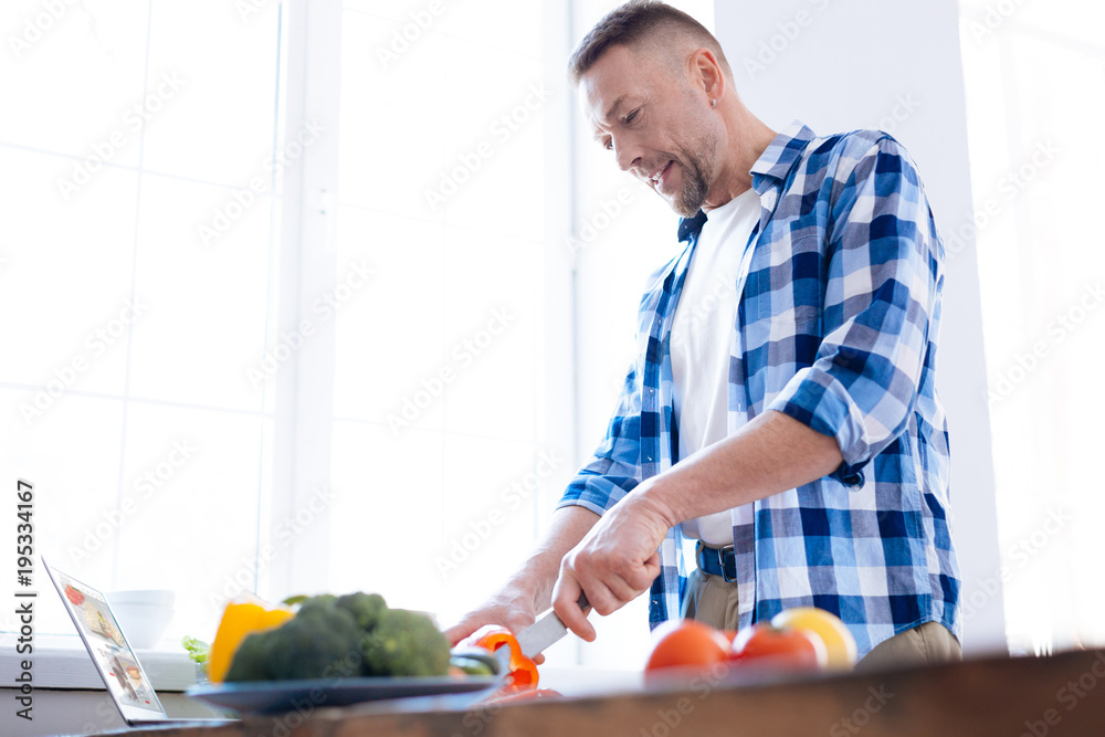 Food is fuel. Pleasant glad focused man holding knife for chopping salad and consuming vegetables Food is fuel. Pleasant glad focused man holding knife for chopping salad and consuming vegetables