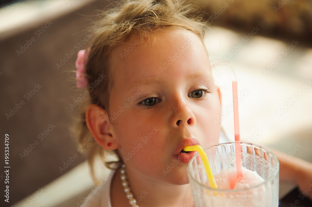 Little girl drinking milkshakes in a cafe outdoors. Little girl drinking milkshakes in a cafe outdoors.