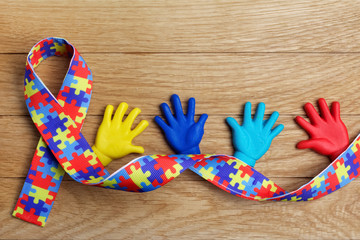 Autism awareness concept with colorful hands on wooden background. Top view