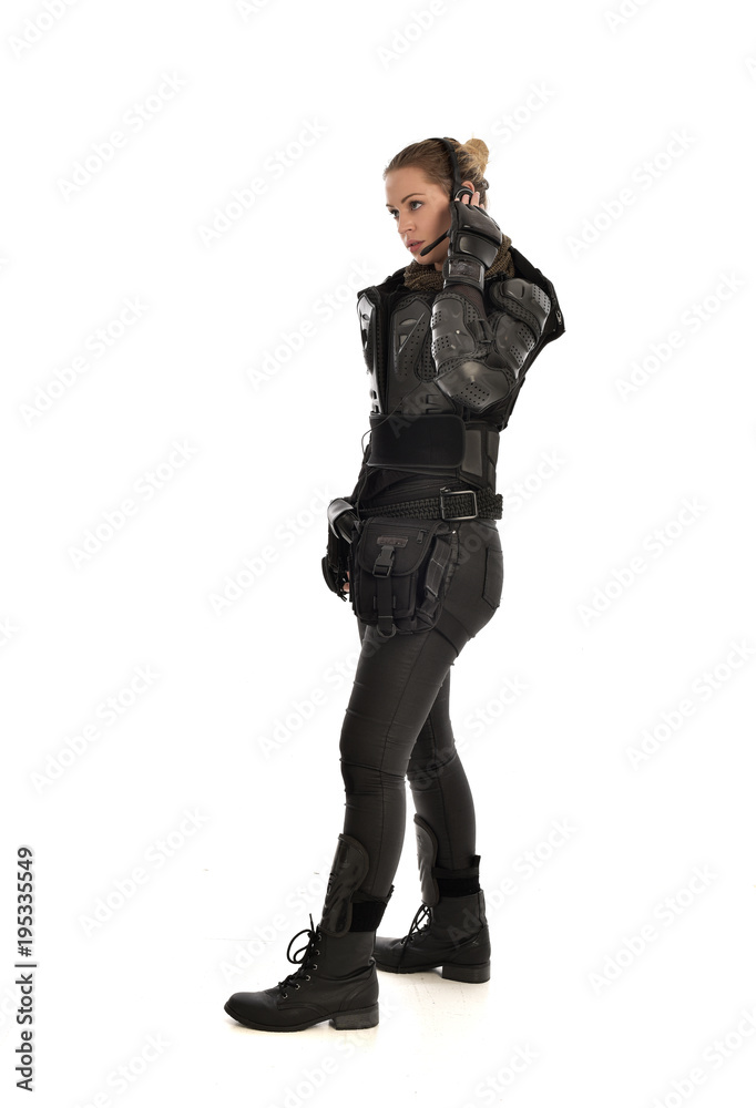 full length portrait of female soldier wearing black tactical armour, standing in side profile, isolated on white studio background. full length portrait of female soldier wearing black tactical armour, standing in side profile, isolated on white studio background.