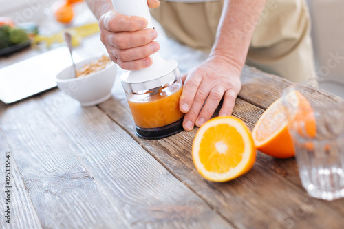 Fresh orange. Selective focus of modern advanced orange fresh machine and male hands holding it