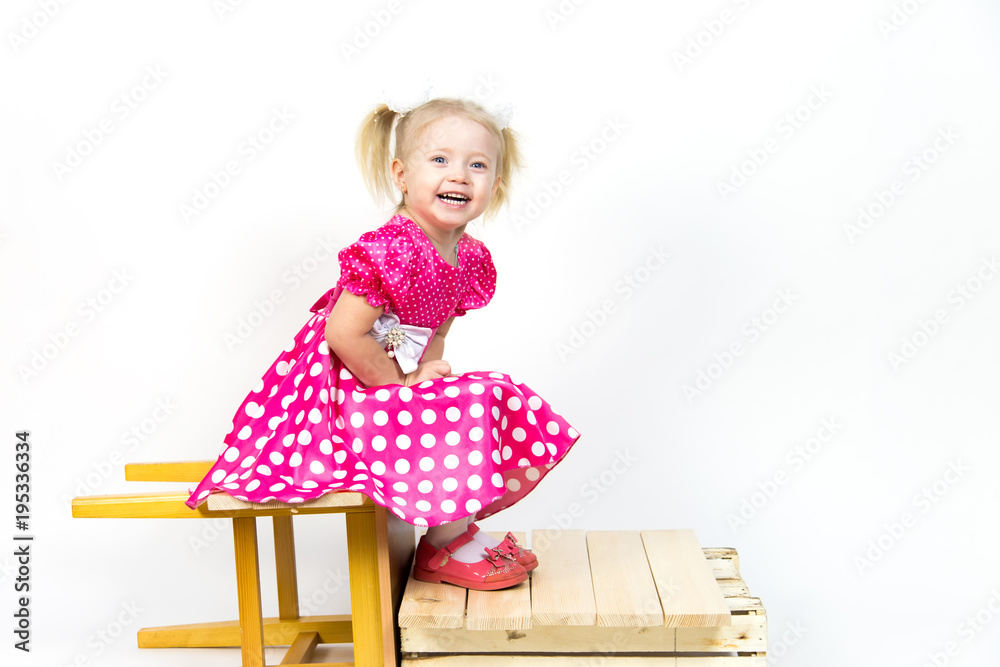 Little girl 3 years old in a red dress with bows in her hair. Beautiful girl in a beautiful fluffy dress posing against a white wall. Little girl 3 years old in a red dress with bows in her hair. Beautiful girl in a beautiful fluffy dress posing against a white wall.