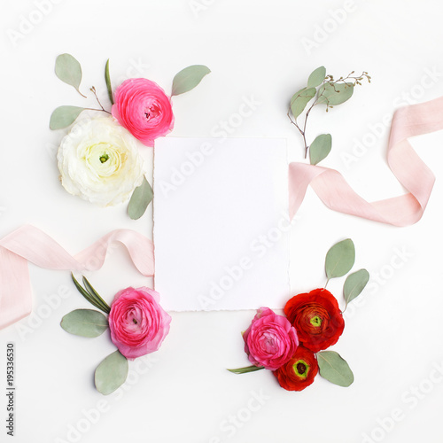 Pink and red ranunculus and green leaves on white background. Flat lay, top view © vetre