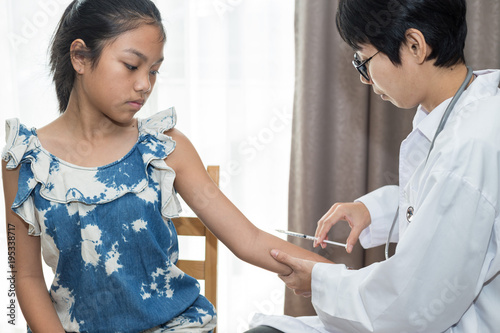 Doctor injecting in arm of asian girl.