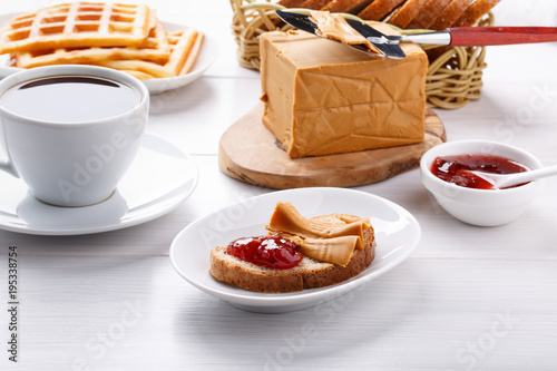 Norwegian brunost on white table. Breakfast with Scandinavian brown cheese, bread and coffee. photo