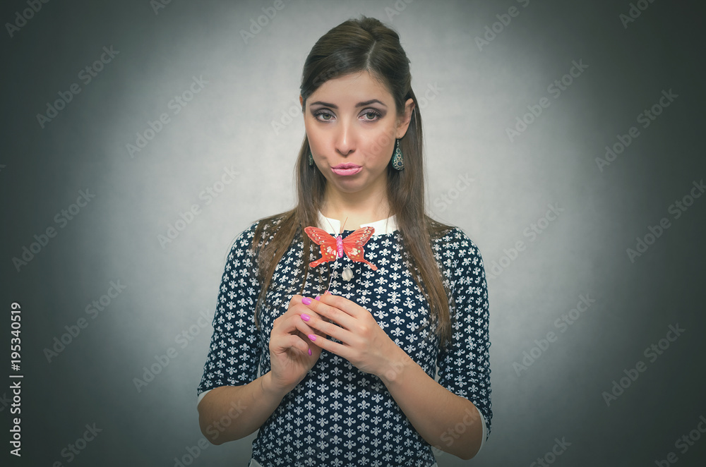 Happy merry unconcern woman holding in hand a toy red butterfly and is amazed. Innocent excited girl concept. Carefree bahavior. Dreaming girl. Happy merry unconcern woman holding in hand a toy red butterfly and is amazed. Innocent excited girl concept. Carefree bahavior. Dreaming girl.