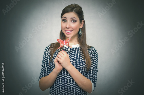 Happy merry unconcern woman holding in hand a toy red butterfly and is amazed. Innocent excited girl concept. Carefree bahavior. Dreaming girl. photo