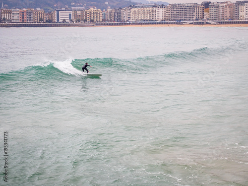 Lonely surfer is surfing on wawes at La Concha Beach in San Sebastian, Basque Country, Spain photo