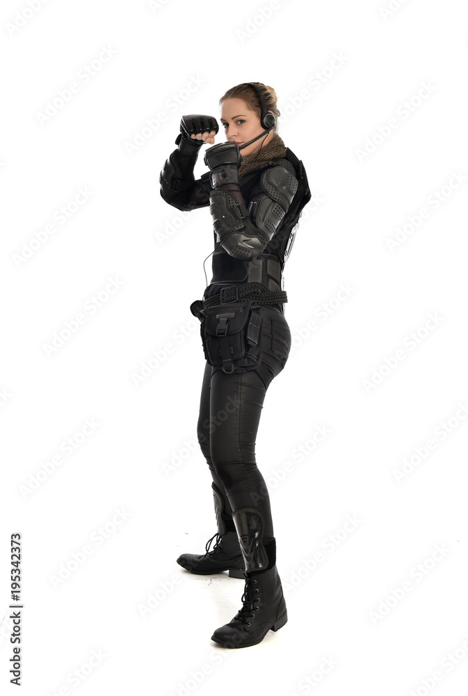 full length portrait of female soldier wearing black tactical armour, standing in side profile, isolated on white studio background. full length portrait of female soldier wearing black tactical armour, standing in side profile, isolated on white studio background.