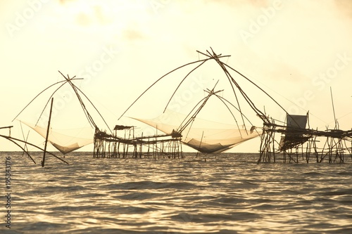 Twilight view of square dip net or Yo made of bamboo in sunset time at Ban Pak Pra -Talay Noi Lake, Phatthalung, Thailand. photo