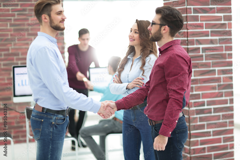 Smiling businessman shaking hands with colleague in office. Smiling businessman shaking hands with colleague in office.