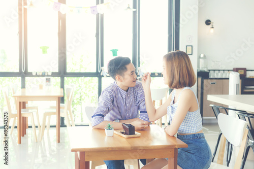 Women lovers feeding a chocolate cake between eating in cafe.