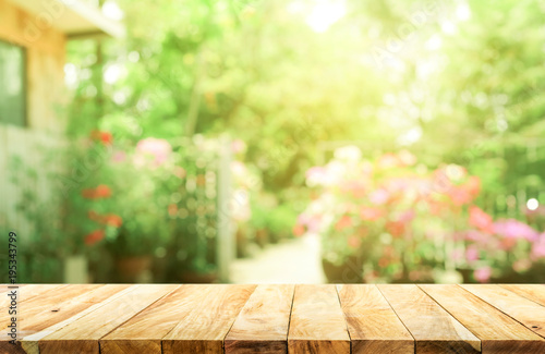 Empty wood table top on blur abstract green from garden and house background