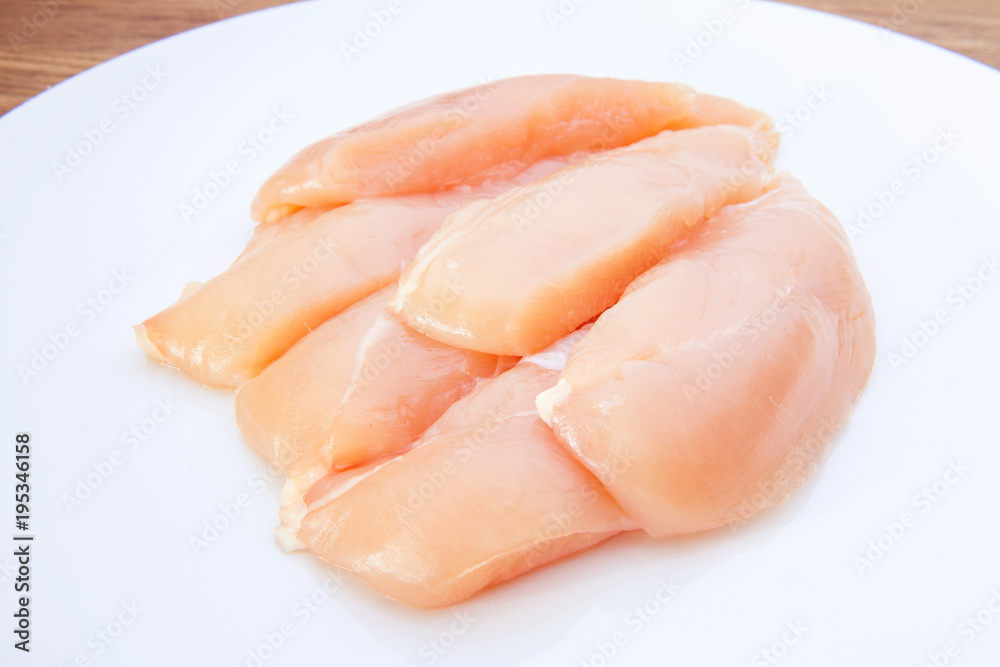 Raw chicken breasts and spices on white plate