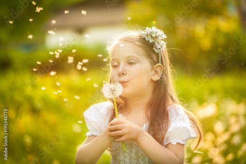 Small girl blowing dandelion