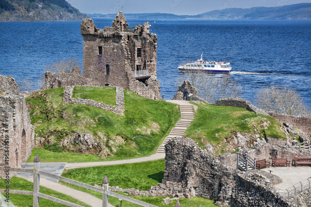 Ruins of Urquhart Castle against boat on Loch Ness in Scotland